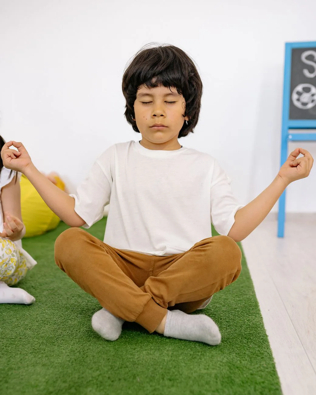 A child sitting calmly in a yoga pose with eyes closed