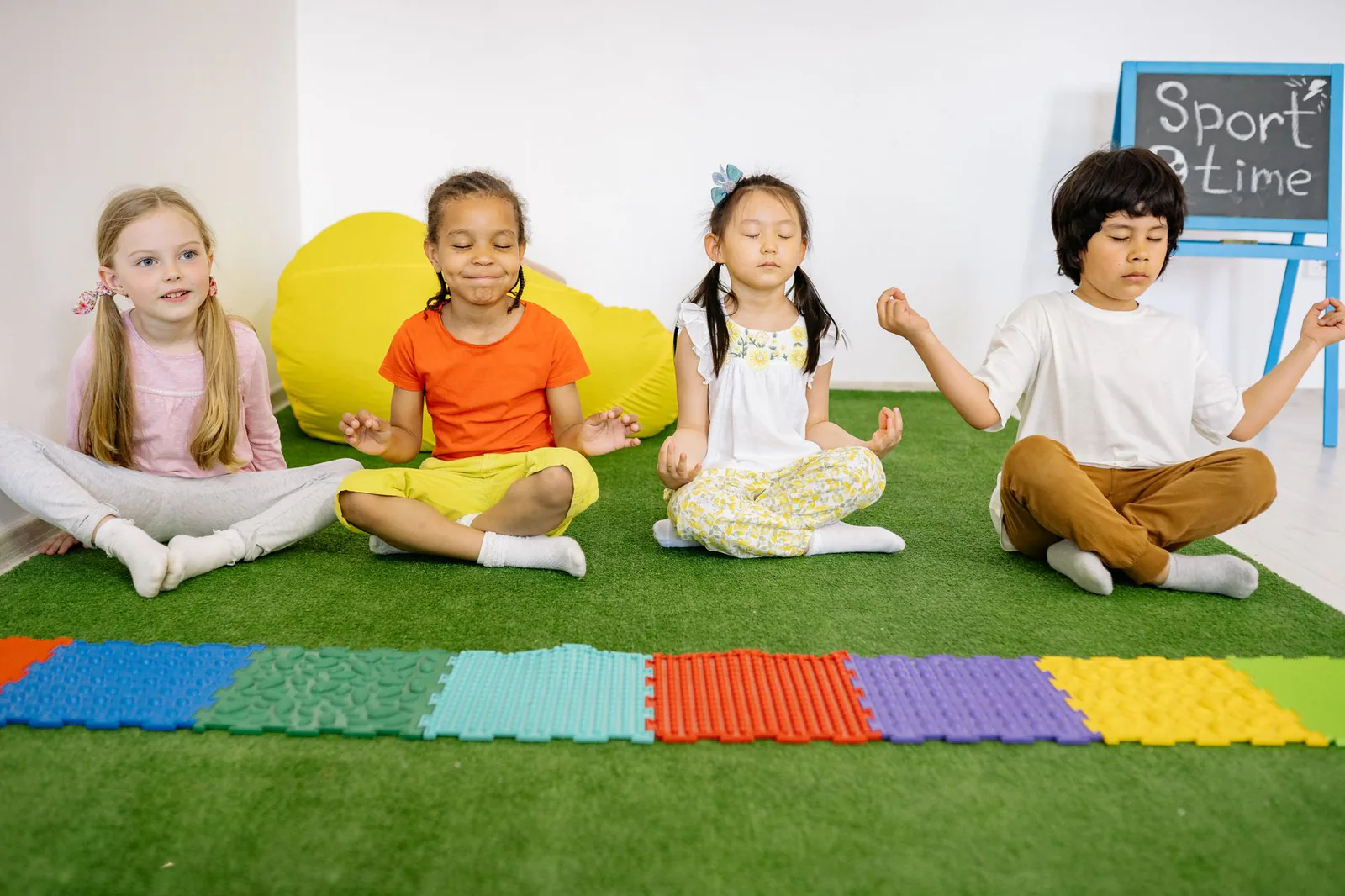 A diverse group of children meditating together on artificial grass